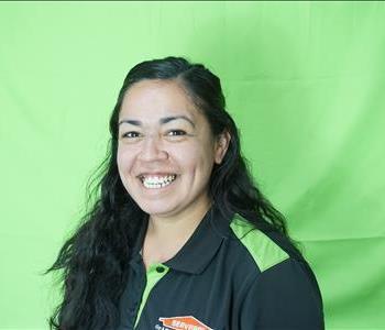 Female employee with black hair in front of green background
